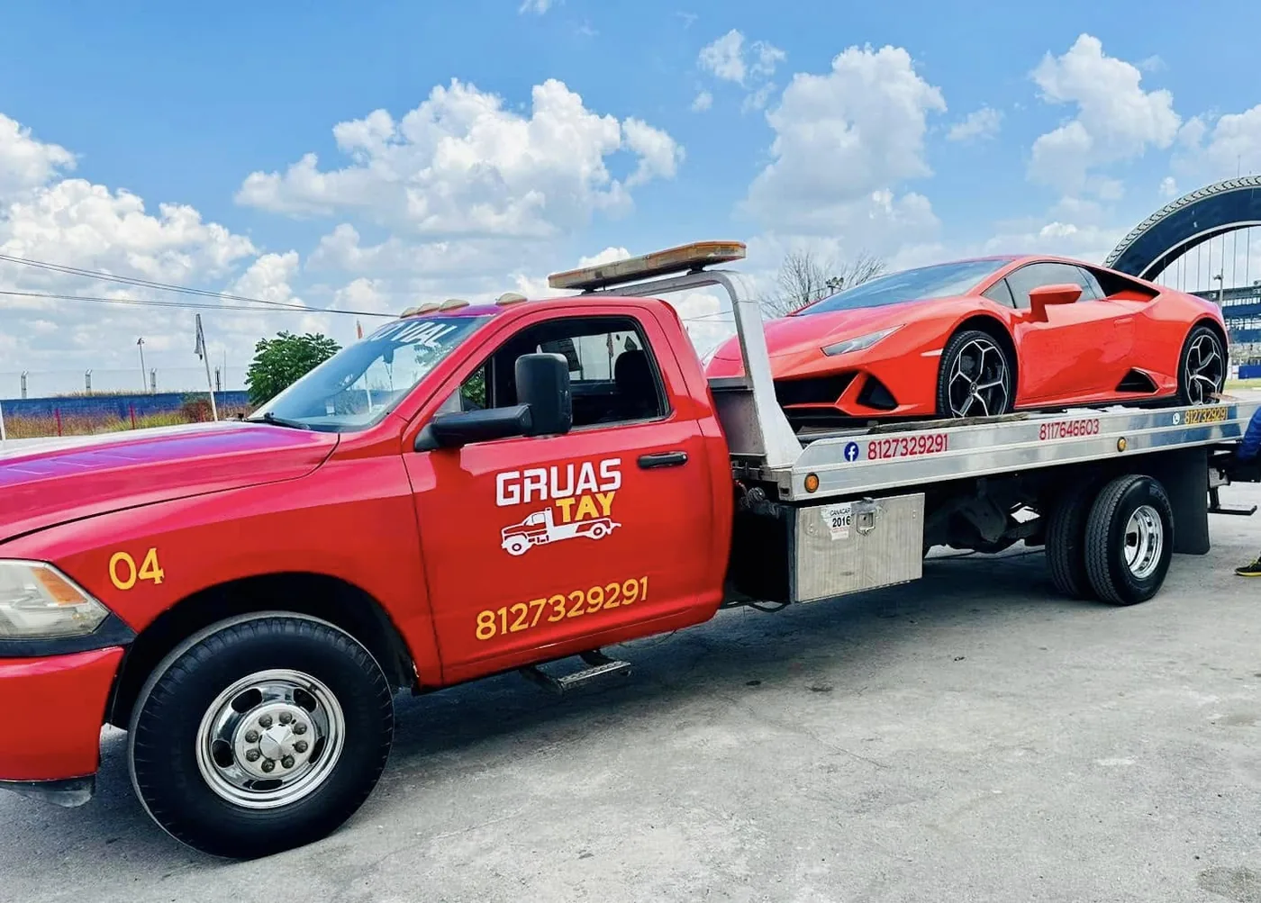 Grúa TAY unidad 04 con plataforma trasladando un auto deportivo rojo en Nuevo León