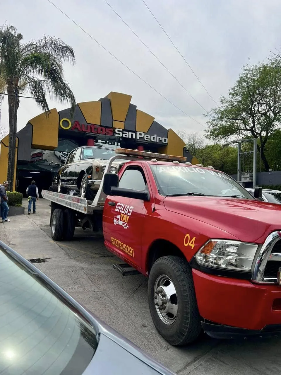 Auto clásico sobre la plataforma de GRUAS TAY frente a una agencia en San Pedro